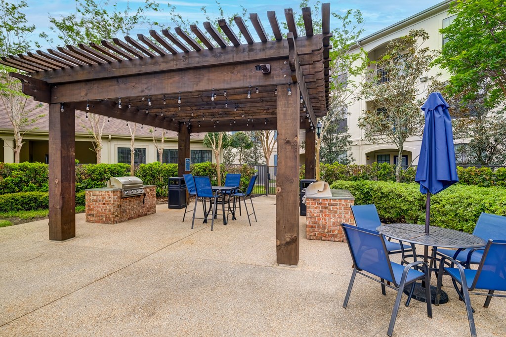 A patio with a table and chairs under a wooden pergola.